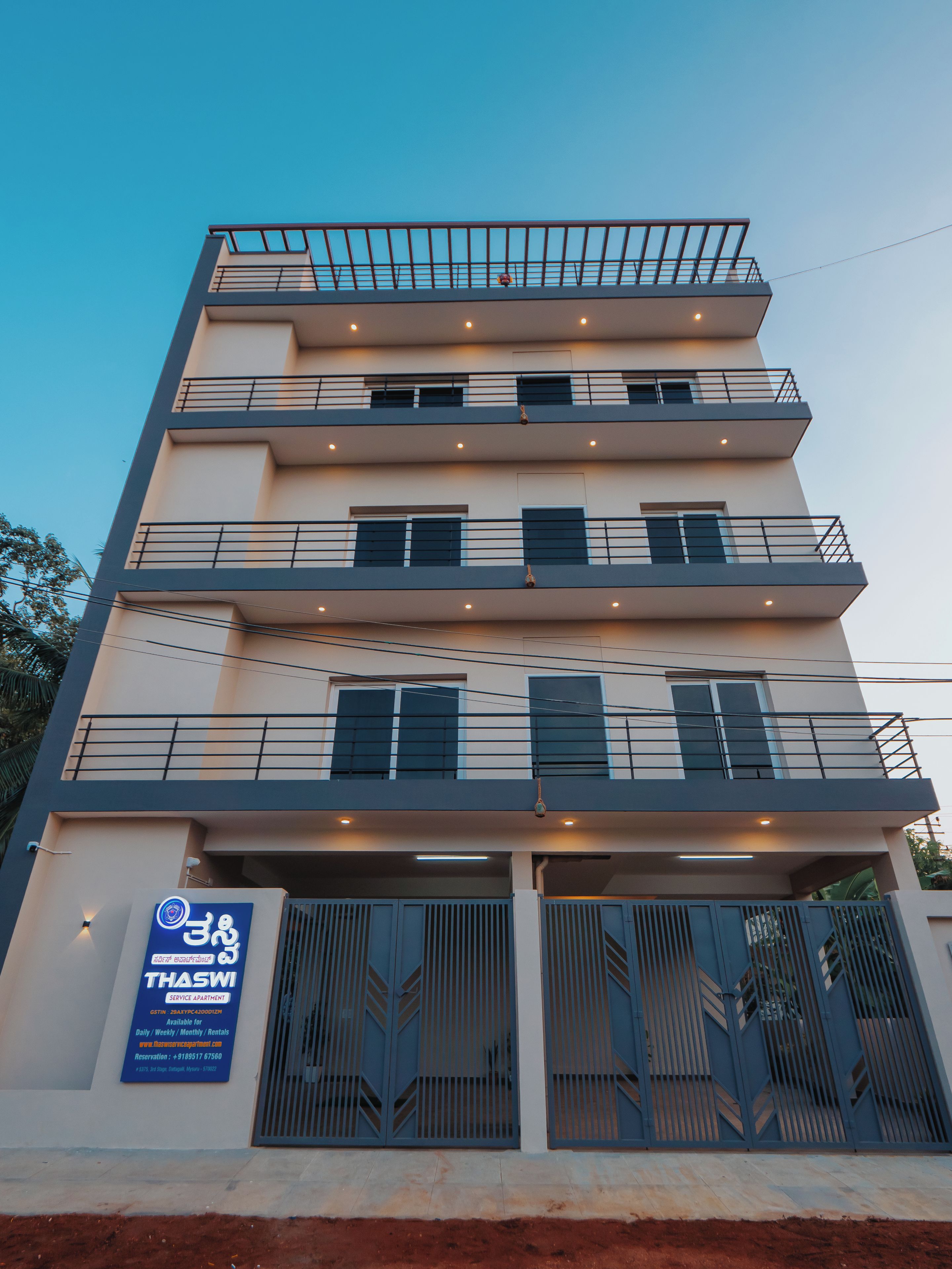 A multi-story building with balconies, a signboard, and a gated entrance.