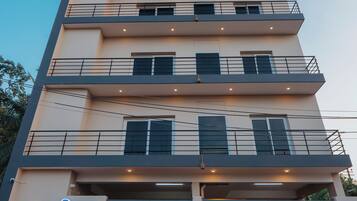 A multi-story building with balconies, a signboard, and a gated entrance.