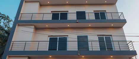 A multi-story building with balconies, a signboard, and a gated entrance.