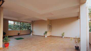 A spacious room with a tiled floor, a large window, and several potted plants.