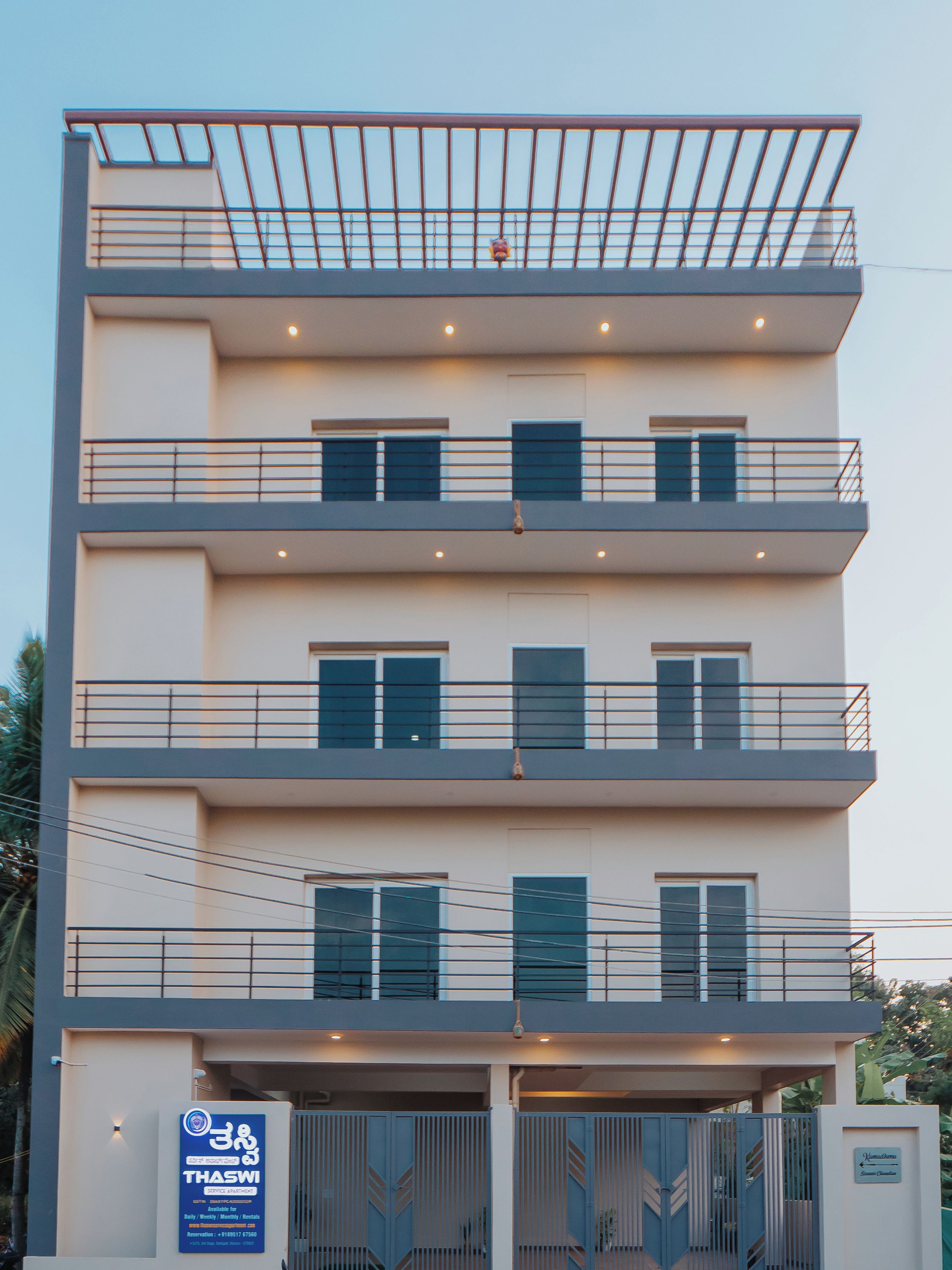A multi-story building with balconies, a gated entrance, and a sign indicating availability for daily, weekly, monthly, and rentals.