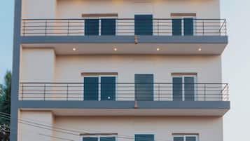 A multi-story building with balconies, a gated entrance, and a sign indicating availability for daily, weekly, monthly, and rentals.