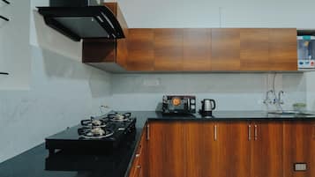 A kitchen with a gas stove, a toaster, and wooden cabinets.
