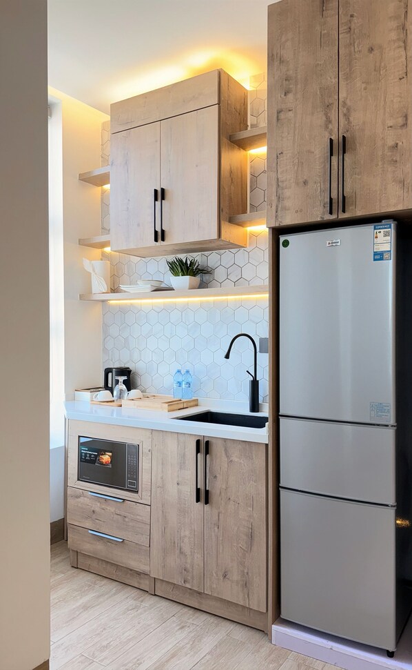 A modern kitchen with wooden cabinets, a stainless steel refrigerator, and a built-in oven.