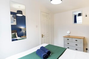 A bedroom with a bed, a dresser, a mirror, and a door. - 2/3 BR Duplex House | Sleeps 6 | 2-minute walk from Camden Town Tube Station (London)