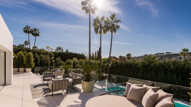 A rooftop terrace with outdoor furniture, a swimming pool, and palm trees under a clear sky. - Vrbo Property (Nueva Andalucía)