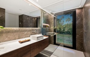 Ein modernes Badezimmer mit einem großen Spiegel, einem weißen Waschbecken und einer Duschkabine aus Glas.