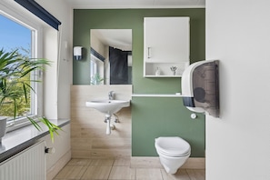 Un baño con lavamanos, inodoro y espejo.