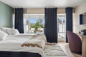 Habitación de hotel con cama, escritorio, silla y vistas al exterior.