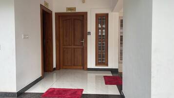 Um corredor com uma porta de madeira, uma porta de vidro e um tapete vermelho no chão.