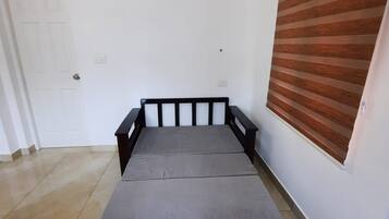 A room with a bed, a door, and a window with blinds.