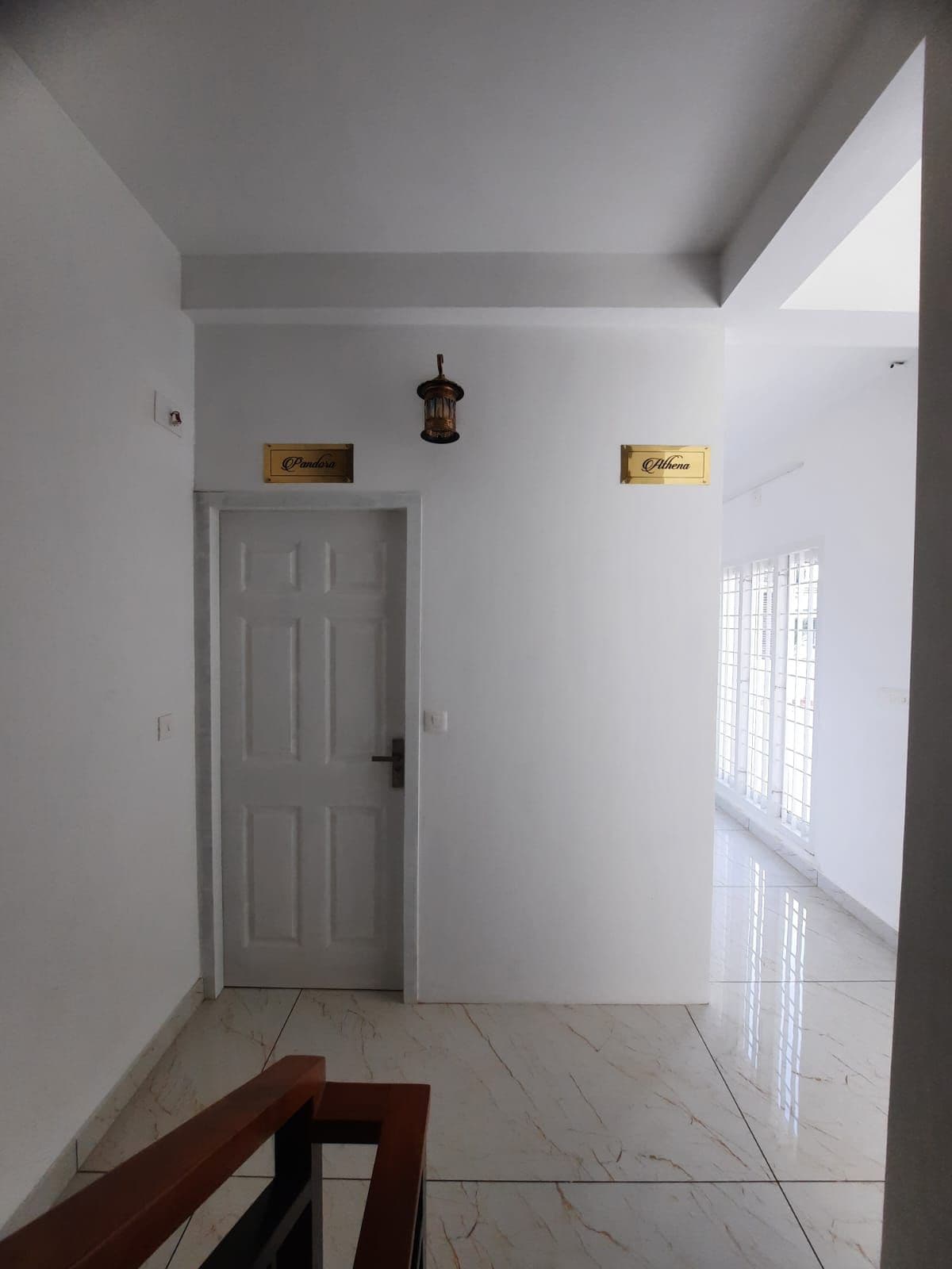 Um corredor com uma porta branca, um banco de madeira e dois sinais na parede.