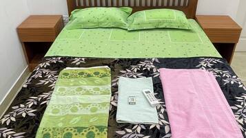 A bed with a wooden frame, two nightstands, and a green bedspread.