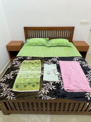 A bed with a wooden frame, two nightstands, and a green bedspread. - THESSALIA (Aluva)