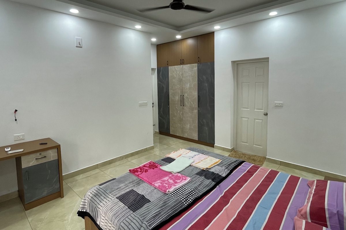 Un dormitorio con cama, escritorio, armario y ventilador de techo.