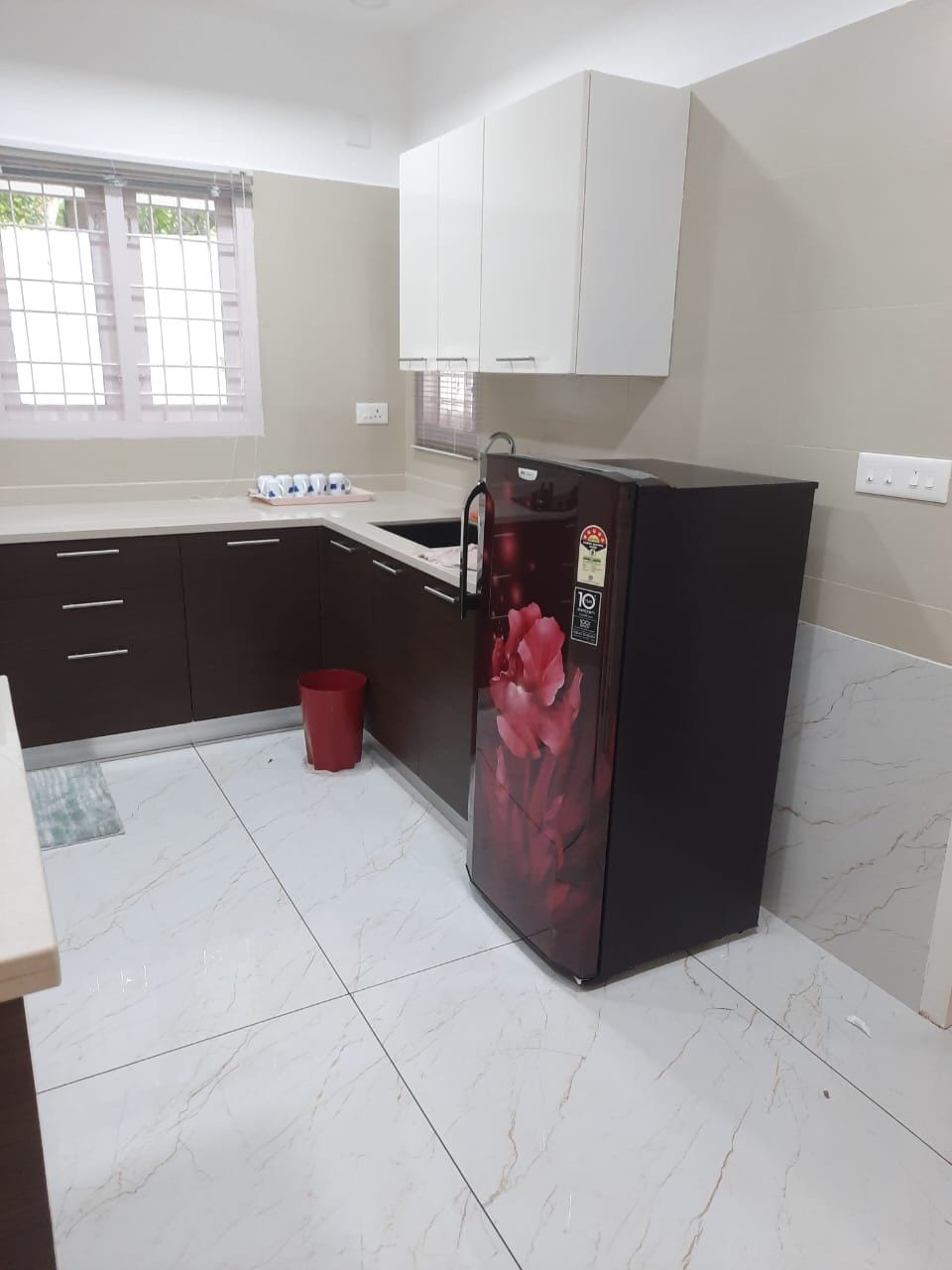 A kitchen with a refrigerator, cabinets, and a window.