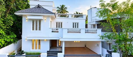 A two-story house with a balcony, a covered patio, and a gated entrance.