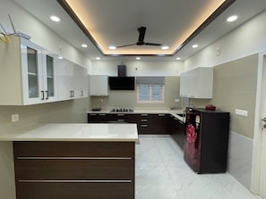 Una cocina moderna con armarios blancos, una isla central y un ventilador de techo.
