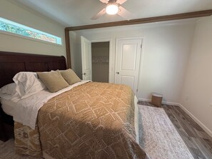 Ein Schlafzimmer mit Bett, Deckenventilator, Fenster und Tür.
