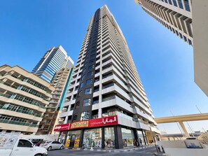 A high-rise building with multiple floors, a supermarket on the ground level, and a clear blue sky in the background. - Luxury 1BR Marina Views Walk to Metro & JBR Beach (Dubai)