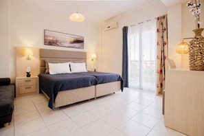 Ein Schlafzimmer mit Bett, Nachttischen, einem Schreibtisch, einem Sessel, einer Pendelleuchte und einem Fenster mit Vorhängen.
