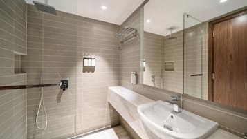 Un baño moderno con ducha, lavamanos y un espejo grande.