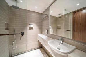 A modern bathroom with a shower, a sink, and a large mirror. - VOCO (Makkah)
