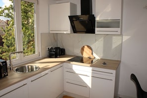 A compact kitchen with a built-in stove, a sink, and a window with a view of greenery.