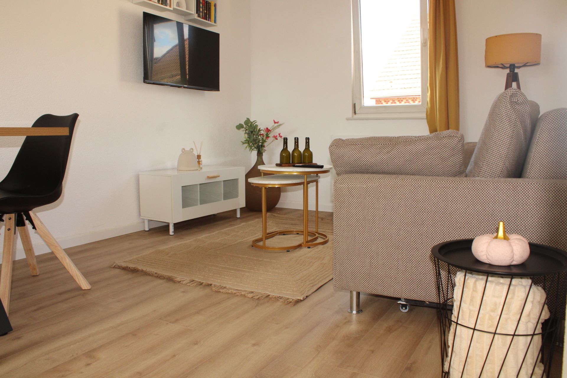 Ein Wohnzimmer mit einer Couch, einem kleinen Tisch, einem Sessel, einem Fernseher und einer Lampe.