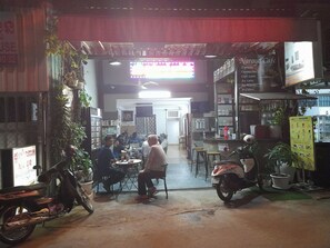 A café interior with tables and chairs, a counter, and a menu board. - Naraya Guesthouse (Phnom Penh)