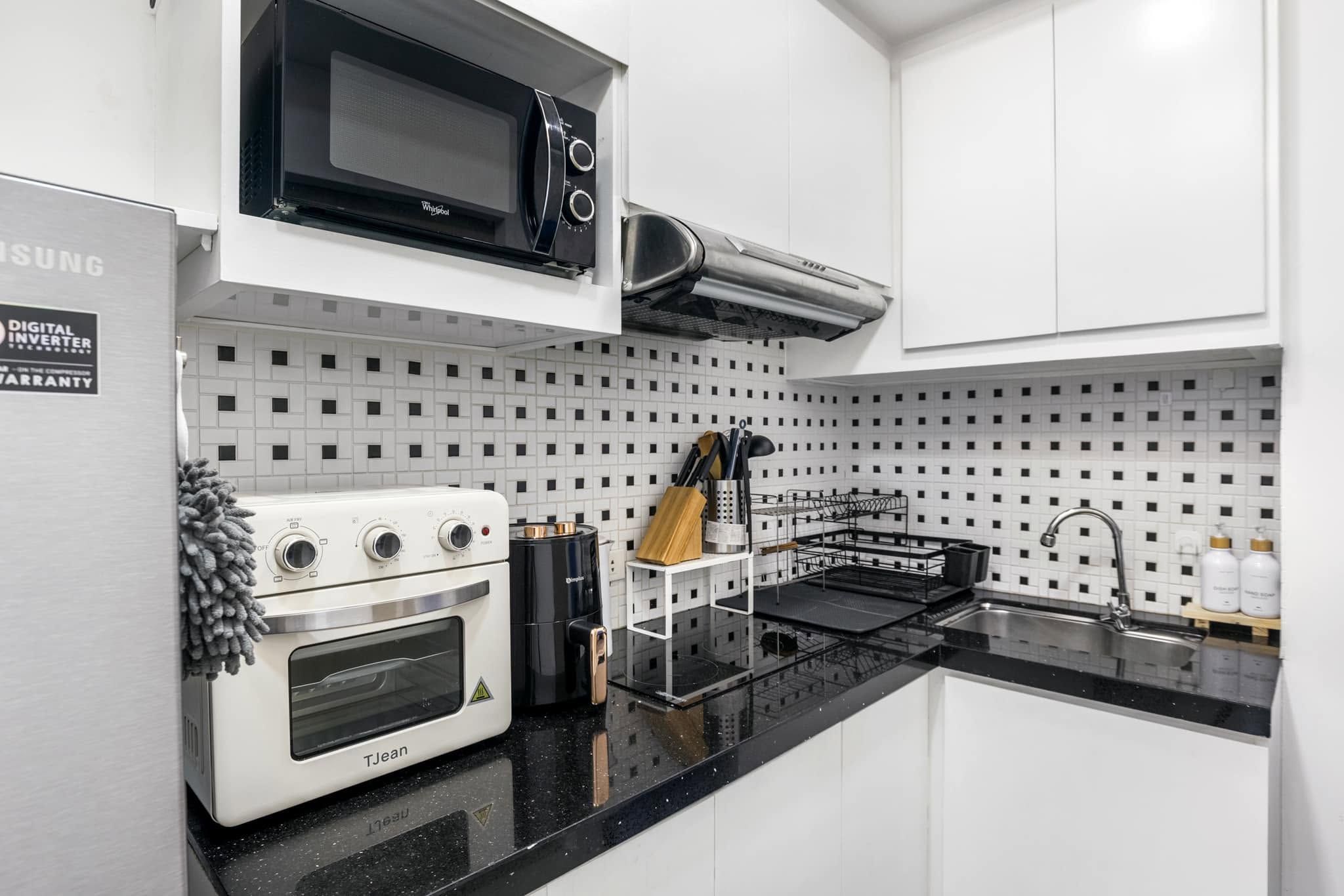 A modern kitchen with a built-in microwave, oven, and stove, featuring a black countertop and white cabinetry.