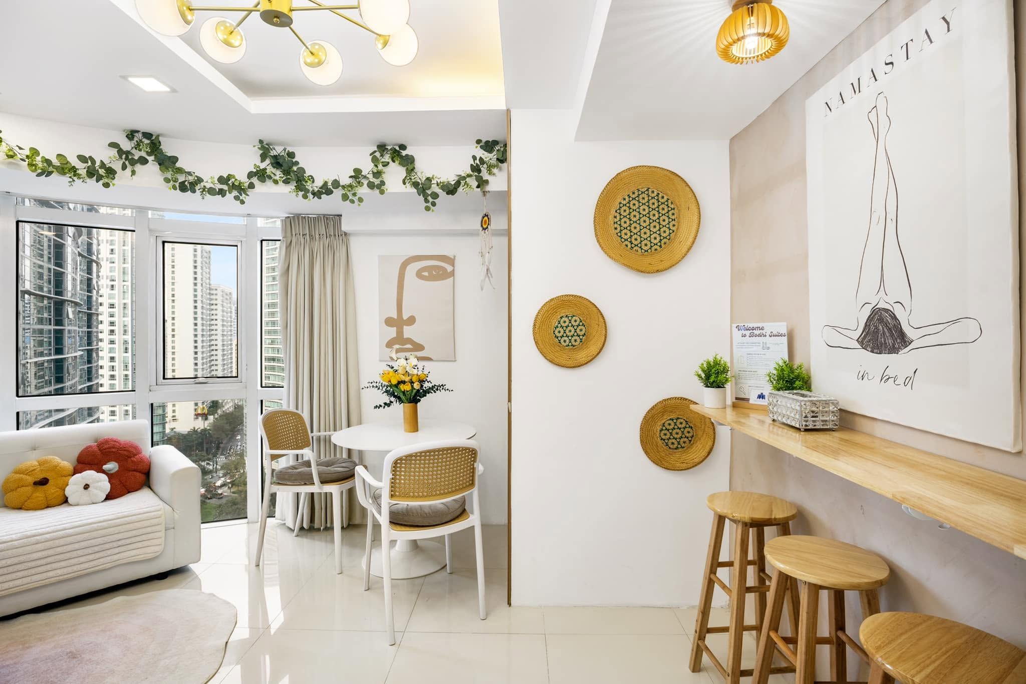 A modern living room with a sofa, dining table, chairs, and a kitchen area with stools.