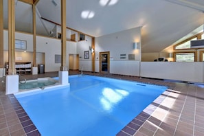 Piscina interior com superfície de água azul cristalina, área de vestiários e balcão de recepção.