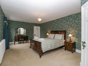 A bedroom with a wooden bed, a dresser, a mirror, and two bedside lamps. - Kylemore (Glastonbury)