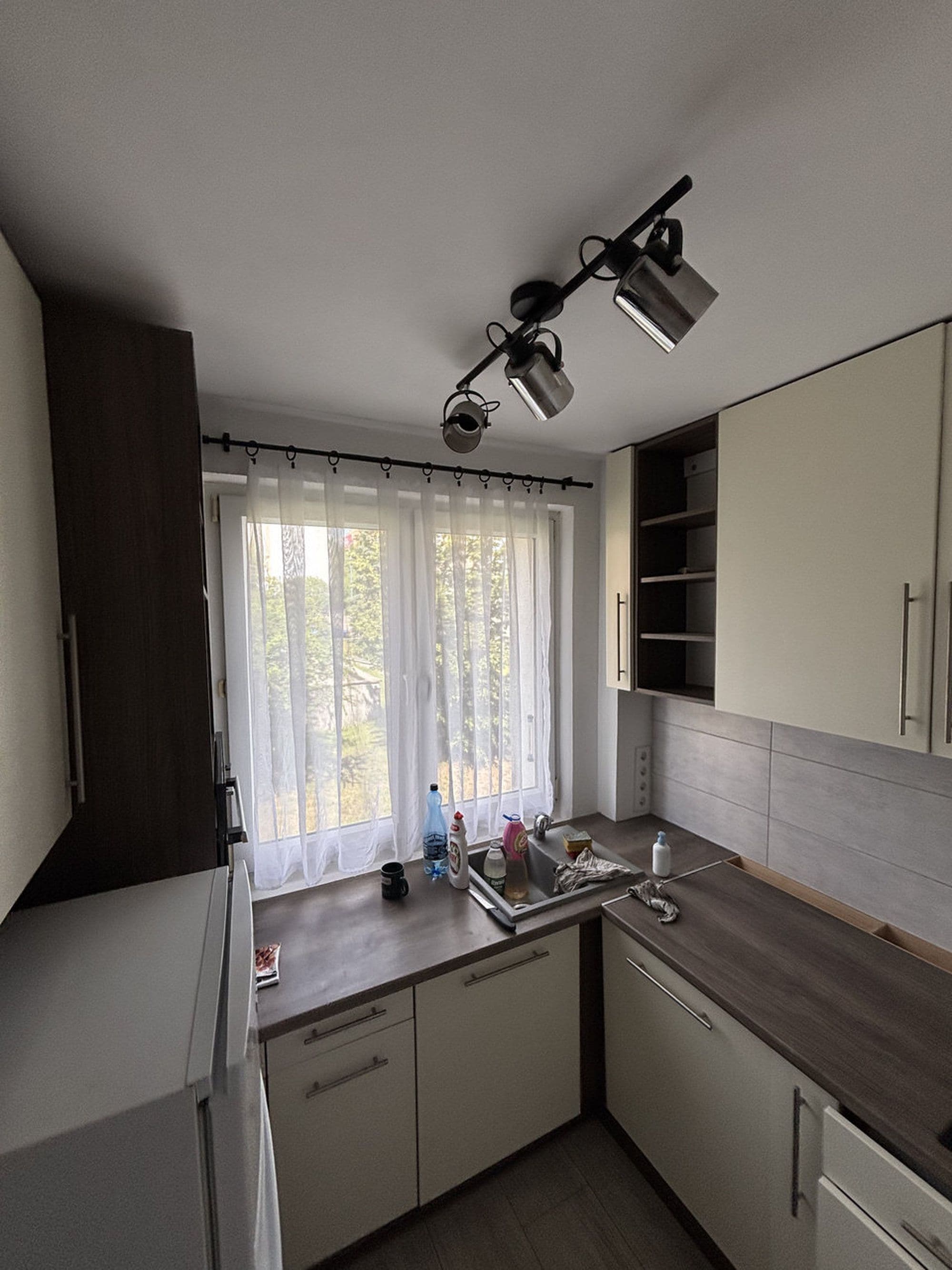 Een moderne keuken met een raam, een spoelbak en kastjes.