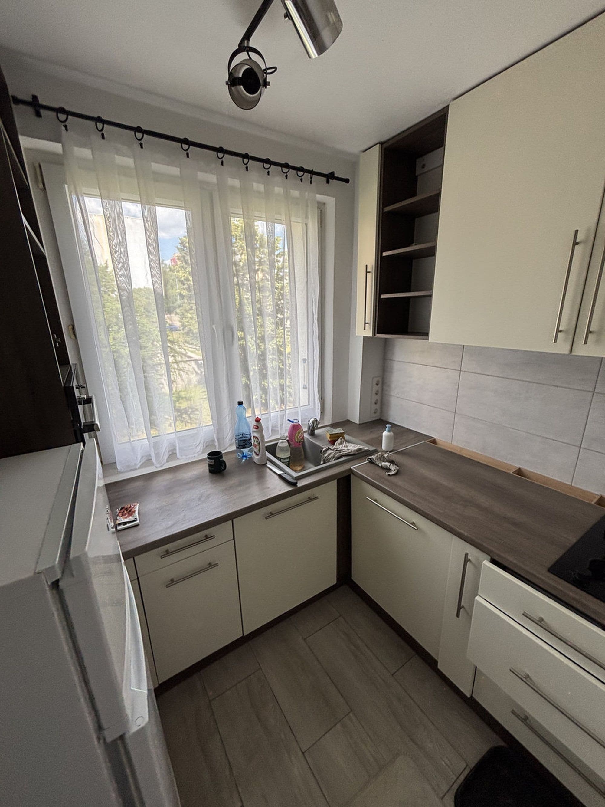 Una cocina con ventana, lavamanos y armarios.