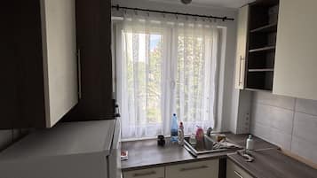 A modern kitchen with a built-in oven, a window with sheer curtains, and a ceiling-mounted light fixture.