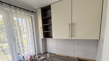 A compact kitchen with a window, a sink, a stove, and cabinets.