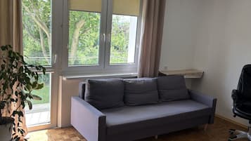 Una habitación con un sofá, una planta en maceta, un escritorio y una silla.