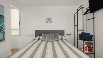 A single-bed room with a striped bedspread, a headboard, and a shelf with folded towels.