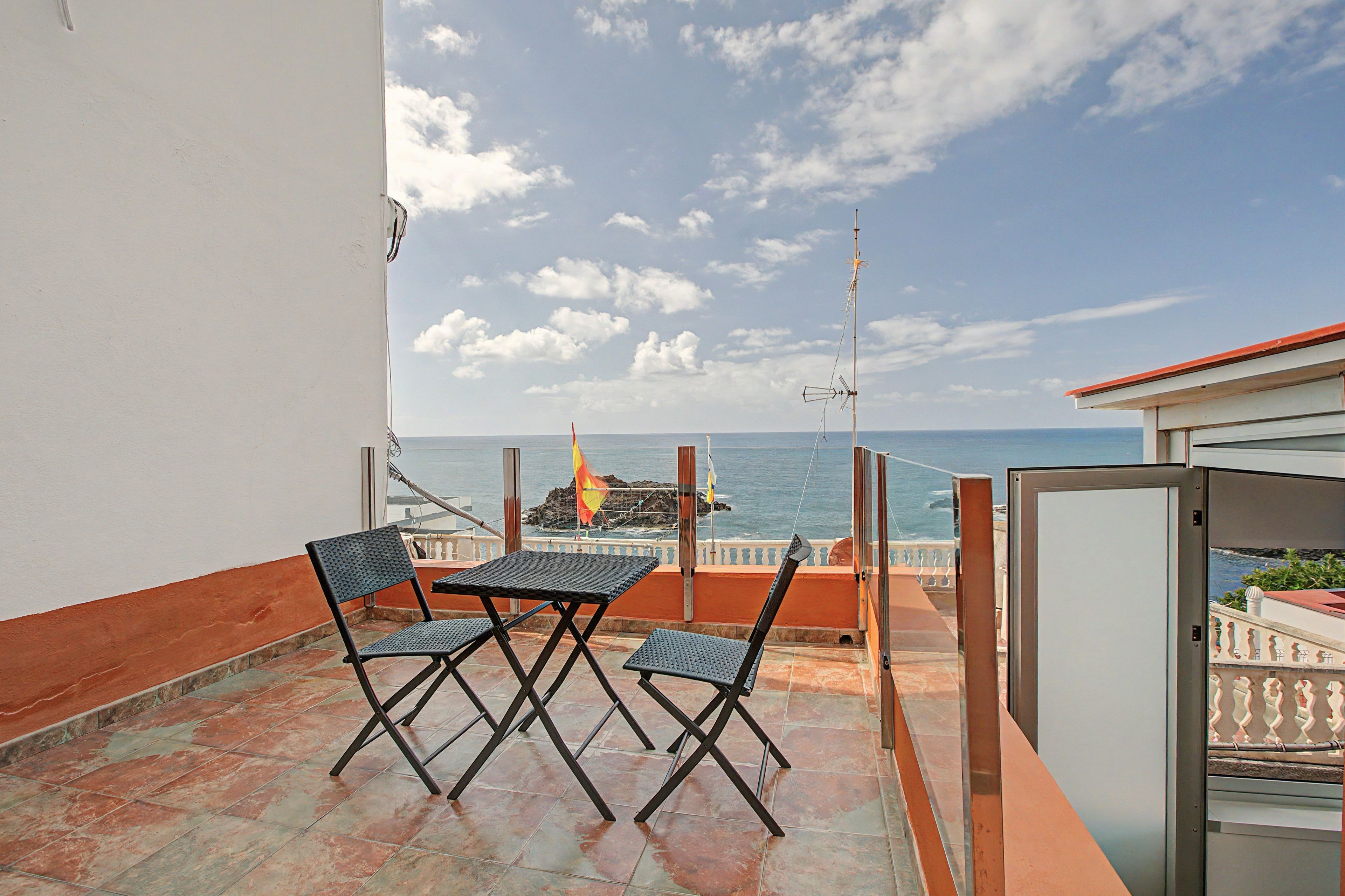 Ein Balkon mit Tisch und Stühlen mit Blick auf das Meer.