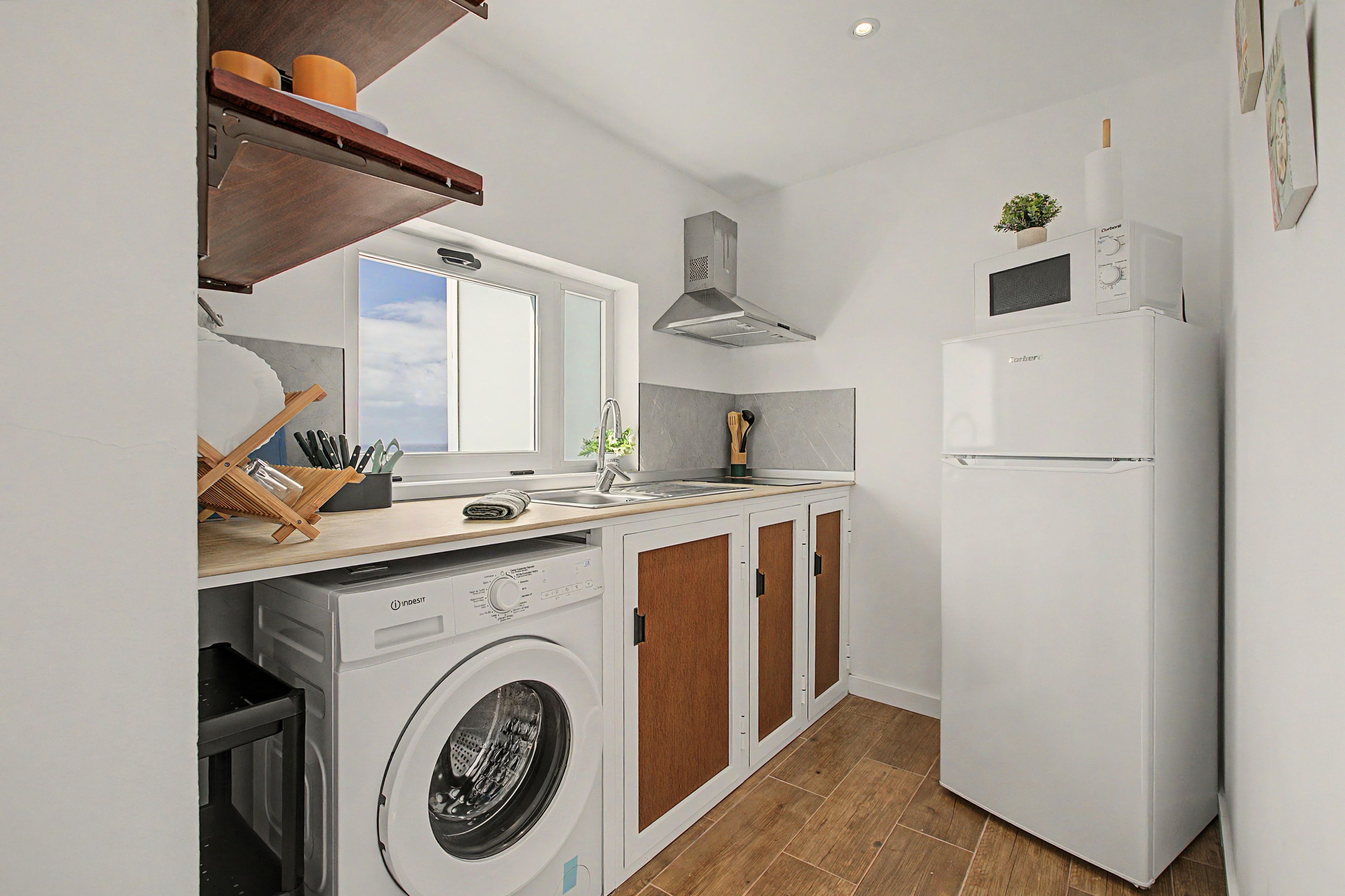 A compact kitchen with a washing machine, a built-in oven, and a refrigerator.