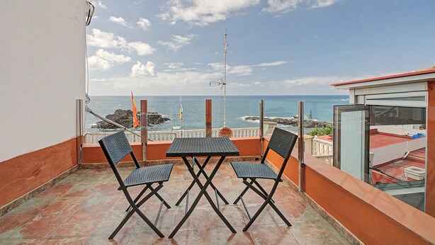 Ein Balkon mit Tisch und Stühlen mit Blick auf das Meer.