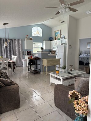 A living room with a sofa, a coffee table, and a dining area with a chair and table. - 3 bed home on a GOLF COURSE in Haines City with PRIVATE POOL and CLOSE TO DISNEY (Haines City)
