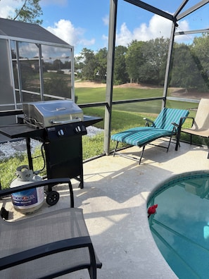 A covered outdoor area with a grill, lounge chairs, and a pool. - 3 bed home on a GOLF COURSE in Haines City with PRIVATE POOL and CLOSE TO DISNEY (Haines City)