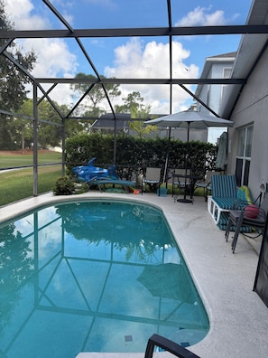 A swimming pool with a covered area, lounge chairs, and a patio umbrella. - 3 bed home on a GOLF COURSE in Haines City with PRIVATE POOL and CLOSE TO DISNEY (Haines City)