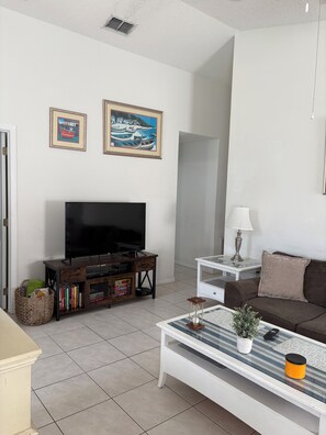 A living room with a flat-screen TV, a coffee table, a sofa, and two framed pictures on the wall. - 3 bed home on a GOLF COURSE in Haines City with PRIVATE POOL and CLOSE TO DISNEY (Haines City)