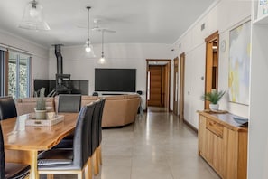 A modern living room with a large flat-screen TV, a fireplace, and a dining area with a wooden table and chairs.
