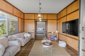 A modern living room with a sofa set, a coffee table, a TV, and a large window.