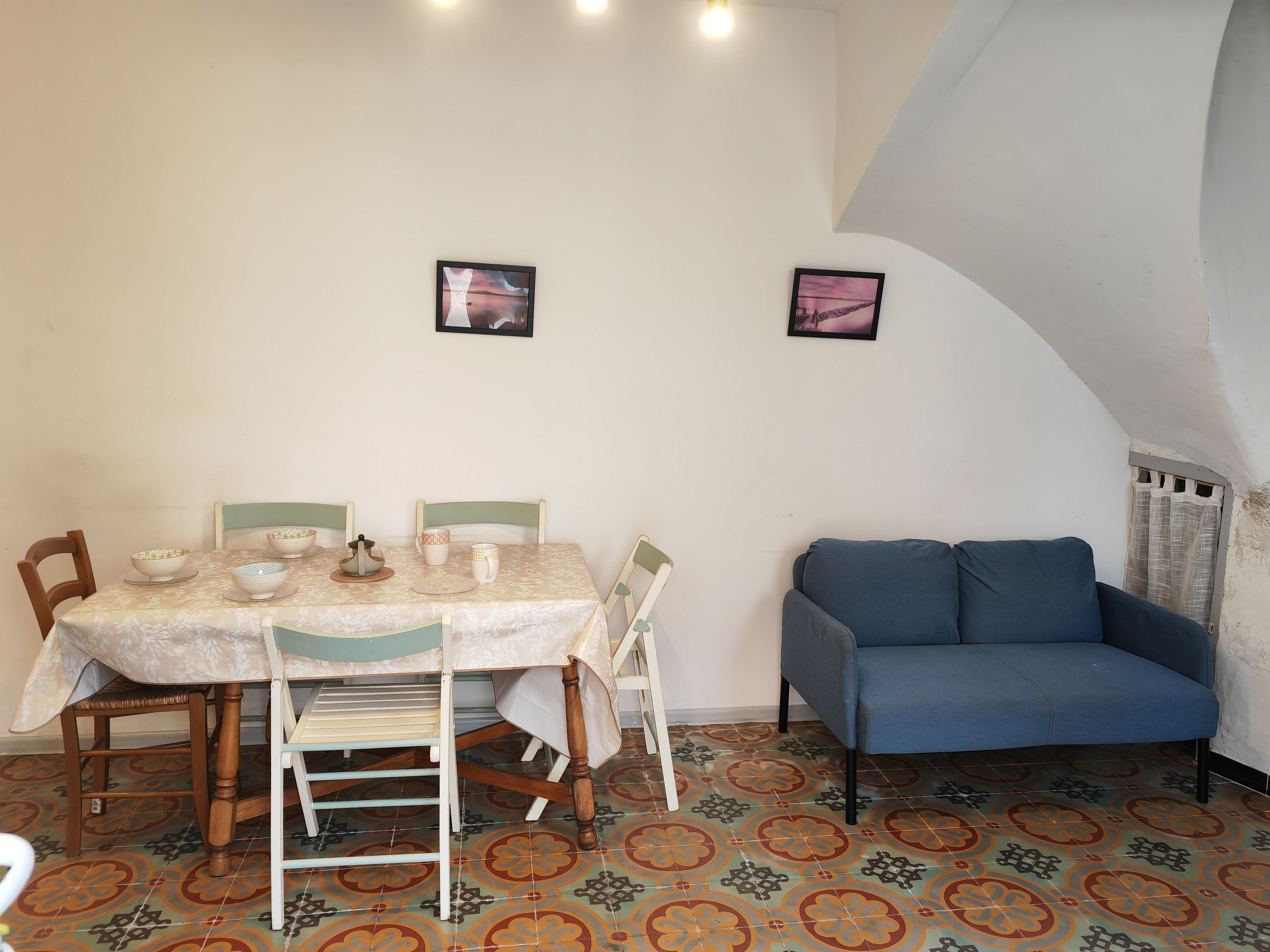 Ein Essbereich mit einem Tisch für vier Personen, zwei Stühlen, einer Couch und zwei gerahmten Bildern an der Wand.